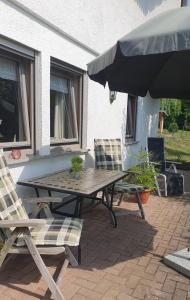 a picnic table and two chairs and an umbrella on a patio at Ferienwohnung am Rebhang in Sasbachwalden