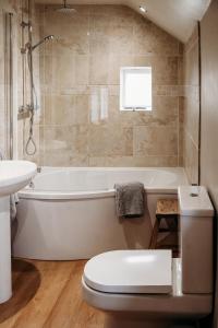 a bathroom with a tub and a toilet and a sink at Staneve Cottage in Docking +12 photos