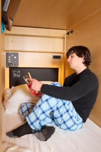 a young man sitting on a bed reading a book at Capsule Residence in Montreal +46 photos