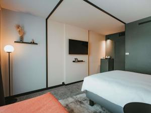 a bedroom with a white bed and a flat screen tv at Novotel Lens Noyelles in Noyelles-Godault