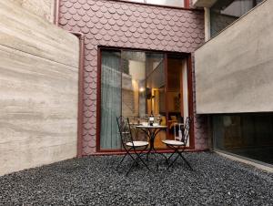 a patio with two chairs and a table in front of a building at Fervença Apartments in Vila Nova de Gaia