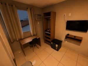 a small room with a television and a desk and a window at DLUX Hotel in Campos dos Goytacazes