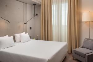 a bedroom with a large white bed and a chair at NH Pisa in Pisa