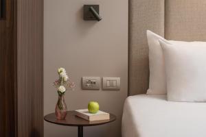 a hotel room with a bed and a vase of flowers on a table at NH Pisa in Pisa