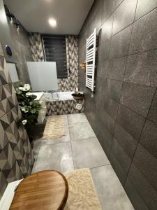 a bathroom with a toilet and a tub and a table at Panorama Apartament in Poznań