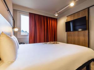 a bedroom with a large white bed with a flat screen tv at ibis Metz Centre Cathedrale in Metz