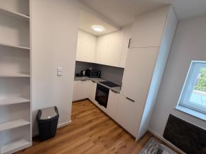 a small kitchen with white cabinets and a window at HeideSuite Soltau in Soltau +5 photos