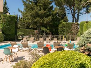 a group of chairs and tables next to a pool at ibis Avignon Sud in Avignon