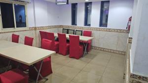 a dining room with red chairs and tables and windows at فندق المرجان للخدمات الفندقية in Jarwal