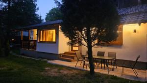 a house with a table and chairs and a tree at Cabana Valea Brândușelor in Bran