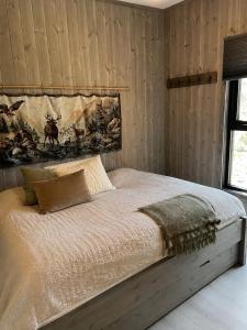 a bed in a bedroom with wooden walls at Peaceful lakefront cabin in Tjaldal