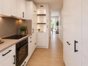 a kitchen with white cabinets and a stove top oven at Kiefernhuus 3 in Norderney