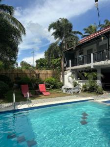 a swimming pool with two chairs and a house at serenity suites tagaytay in Tagaytay