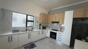 a kitchen with white cabinets and a sink and a window at SiwelaNest in Mbabane +1 photo