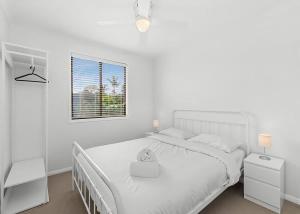 a white bedroom with a white bed and a window at Mindil Arch Walk to 3 Beaches & River in Tomakin