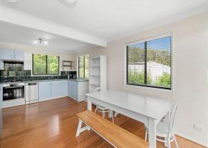 a kitchen with white cabinets and a white dining table at Mindil Arch Walk to 3 Beaches & River in Tomakin +9 photos