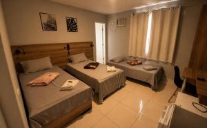 a room with two beds and a television in it at DLUX Hotel in Campos dos Goytacazes