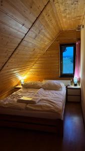 a large bed in a wooden room with a window at Ranczo Obozin 62 in Obozin