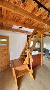 a loft bed in a room with a wooden ceiling at Ranczo Obozin 62 in Obozin