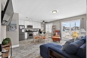 a living room with a blue couch and a kitchen at Radiant Beach Block Condo Parking Patio in Brigantine