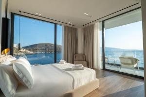 a bedroom with a large white bed and large windows at Nube Luxury Villas in Sarandë