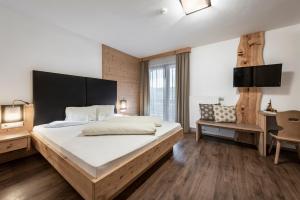a large bedroom with a large bed and a chair at Der Brunnerhof in Mühlbach +34 photos