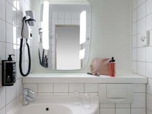 a bathroom with a sink and a mirror at Ibis Hotel Köln Am Dom in Cologne +70 photos
