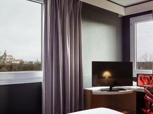 a room with a window with a desk and a monitor at Ibis Provins in Provins