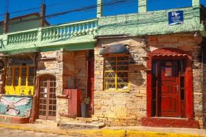 an old brick building with red doors and windows at Pousada 3 Bruxas Casa de Hóspedes in São Thomé das Letras