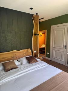 a bedroom with a large white bed with green walls at Cabana Forest in Borşa