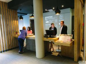 a group of people standing at a reception counter at ibis Alençon in Alençon