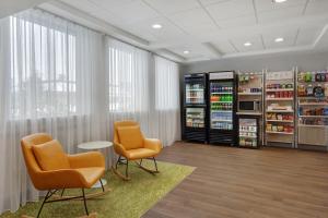 a room with two chairs and a drink cooler at Spark by Hilton Watertown, NY in Watertown