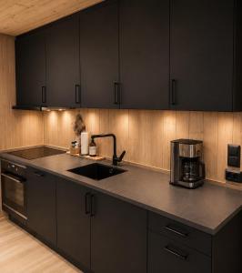 a kitchen with black cabinets and a sink at Peaceful lakefront cabin in Tjaldal