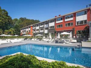 a hotel with a swimming pool in front of a building at Novotel Resort & Spa Biarritz Anglet in Anglet