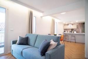 a living room with a blue couch and a kitchen at Appartamento Bianca in Letojanni