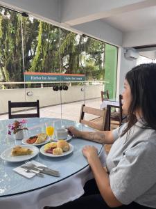 a woman sitting at a table with a plate of food at Harbor Inn Jaraguá in Jaraguá do Sul +7 photos