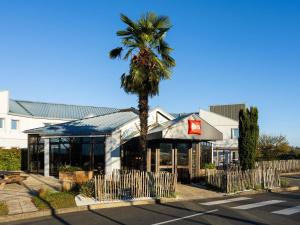 Eine Palme vor einem Gebäude mit einem Restaurant in der Unterkunft Ibis Angoulême Nord in Champniers
