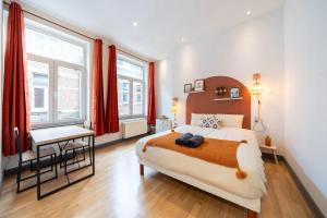 a bedroom with a bed and a desk and windows at Le West - Dinant Centre in Dinant