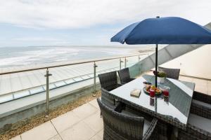 a table with an umbrella on a balcony with the ocean at 3 Bed in Bideford oc-52079 in Westward Ho