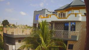 a large building with a balcony and a palm tree at Immanuel Victory Hotel & Restaurant in Ajenkotoku