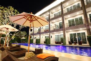 a hotel with chairs and an umbrella next to a swimming pool at The Malika Hotel - SHA Extra Plus in Phuket Town