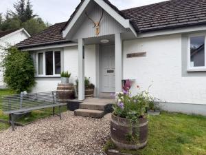a white house with a bench in front of it at MHOR 84 in Kingshouse