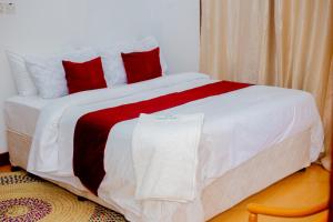 a large bed with red and white sheets and pillows at Furavia Hotel stay in Moshi