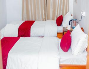 two beds in a room with red and white pillows at Furavia Hotel stay in Moshi