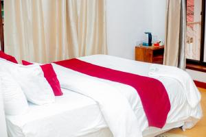 a bed with a red and white blanket on it at Furavia Hotel stay in Moshi