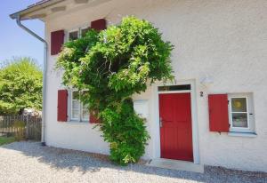 a red door on a white house with red shutters at Vacation apartment Stüble in Aichstetten