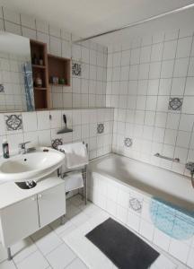a white bathroom with a sink and a tub and a mirror at Vacation apartment Stüble in Aichstetten +21 photos