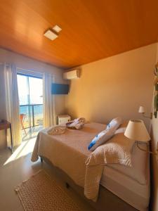 ein Schlafzimmer mit einem Bett, einer Lampe und einem Fenster in der Unterkunft Casa Sol da Ilha in Angra dos Reis