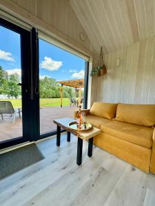 a living room with a couch and a table at Rātes Krasti - Rasa - holiday house with sauna and lakeview in Lejasciems +21 photos