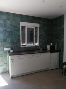a kitchen with a counter with a sink and a window at Finca Laxuan in Cádiz